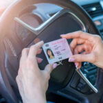 Person holding drivers license inside a car