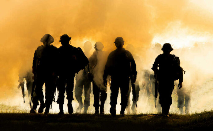Silhouettes of soldiers walking through smoke at sunset