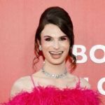 Person in pink outfit smiling in front of backdrop