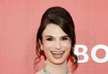 Person in pink outfit smiling in front of backdrop