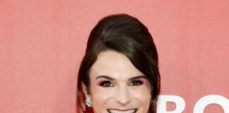 Person in pink outfit smiling in front of backdrop
