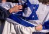 Iranian Missile Strike IGNITES Factory in Israel People holding an Israeli flag together, showcasing unity and cultural pride