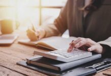 Healthcare Savior or Fiscal Quicksand? Billionaire Tax Examined Person calculating taxes with a calculator and writing notes in a notebook at a desk