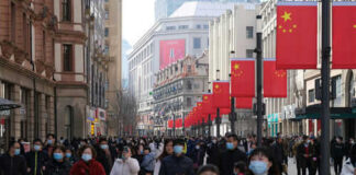 Crowded street with people wearing masks and flags