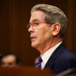 Man in suit speaking at a microphone indoors