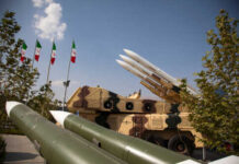 Military missiles displayed outdoors with Iranian flags in the background