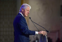 A man in a suit speaking at a podium with a microphone