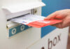 Mail-In Ballot Chaos Ends? Supreme Court Move Looms A hand inserting letters into a mailbox