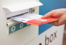 A hand inserting letters into a mailbox