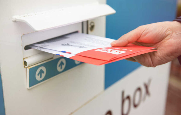 A hand inserting letters into a mailbox