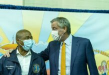 Government Overreach Exposed in NYC Rail Saga Two political leaders wearing masks engage in a friendly conversation at a community event