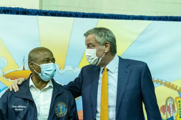 Two political leaders wearing masks engage in a friendly conversation at a community event