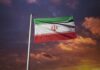 Iranian flag waving against a sunset sky
