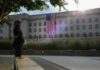 A Marine standing guard in front of the Pentagon with an American flag in the background