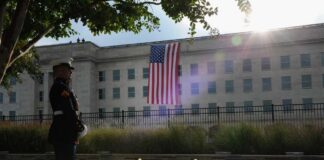 A Marine standing guard in front of the Pentagon with an American flag in the background