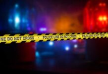 Police crime scene tape with emergency lights in the background