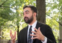 A man in a suit gesturing while speaking outdoors