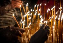 Hands lighting candles during a religious ceremony