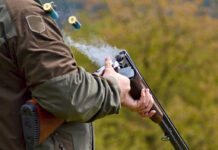 Shotgun Terror Unfolds: 18-Year-Old Attacks School Person reloading shotgun outdoors with cartridges ejecting