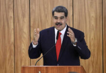 Man speaking at podium with wood panel background