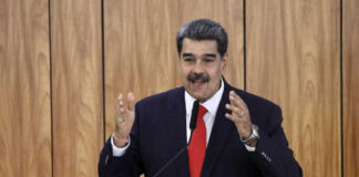 Man speaking at podium with wood panel background