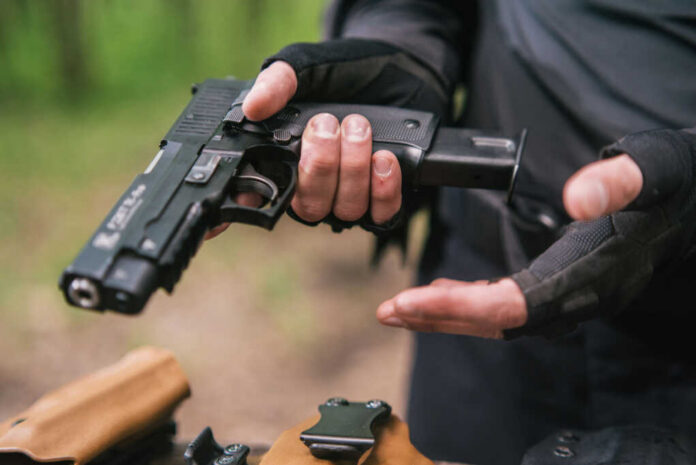 Person holding a handgun with tactical gloves outdoors