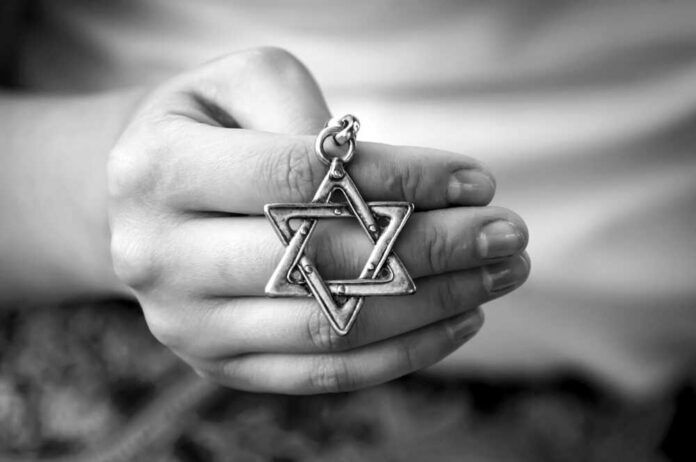 shutterstock_1146802733.jpg A hand holding a silver Star of David pendant