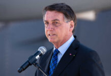 A man in a suit speaking into a microphone at an outdoor event