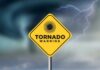 A yellow tornado warning sign against a stormy background