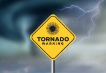 A yellow tornado warning sign against a stormy background