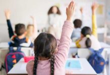 Students in a classroom raising their hands to answer a question
