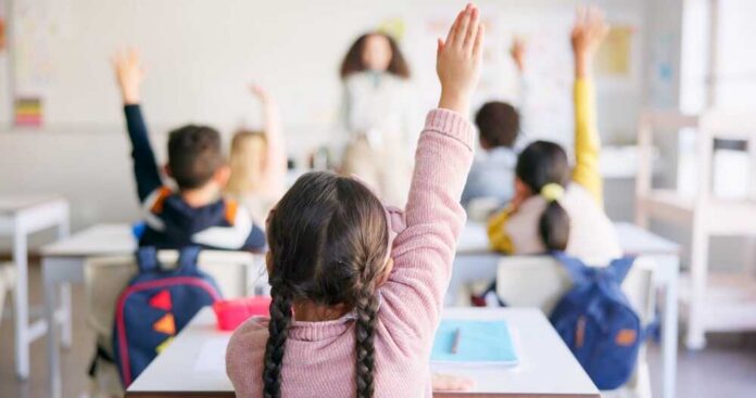 Students in a classroom raising their hands to answer a question