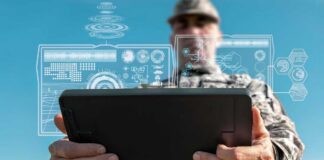 A soldier holding a tablet displaying digital data overlays