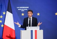 Emmanuel Macron delivering a speech at La Sorbonne with flags in the background
