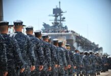 Navy personnel marching in formation towards a ship