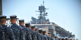 Navy personnel marching in formation towards a ship