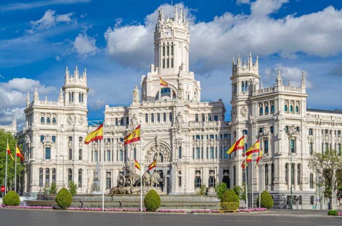 A grand historic building with flags in front and a fountain