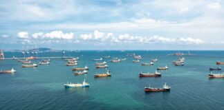 Aerial view of numerous cargo ships anchored in a blue ocean