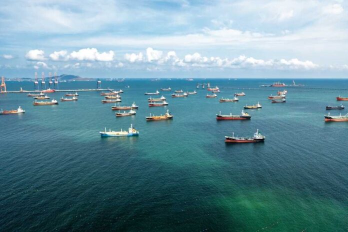 Aerial view of numerous cargo ships anchored in a blue ocean