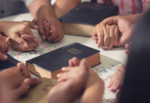 Canada’s Legal Move: Christian Teachings at Risk? People holding hands with Bibles on table