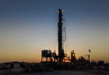 Alaska Oil Boom: Massive Project Ignites U.S. Independence Drilling rig silhouetted against a sunset with workers visible