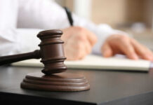 Doctor Hits Man, Flees—JUST 13 Months Jail! Wooden judge's gavel on a desk with a person writing in the background