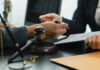Hands of professionals discussing documents beside a judge's gavel