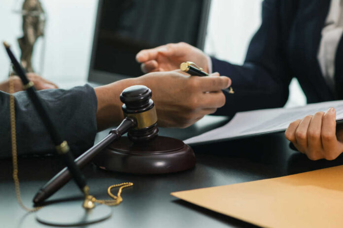Hands of professionals discussing documents beside a judge's gavel