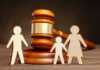 Gavel behind wooden family cutout figures on table