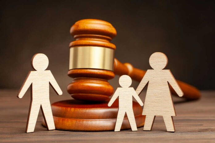 Gavel behind wooden family cutout figures on table