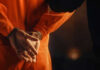 Person in orange jumpsuit with hands cuffed behind