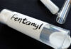 A glass container labeled 'Fentanyl' with a white powder inside