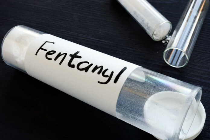 A glass container labeled 'Fentanyl' with a white powder inside