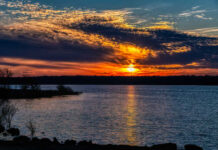 A vibrant sunset over a lake with colorful clouds